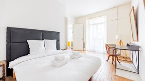 A modern hotel room with a large bed, a desk, and a chair.