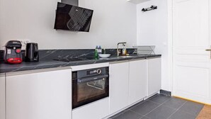 A modern kitchen with a black countertop, white cabinets, a built-in oven, and a black range hood.
