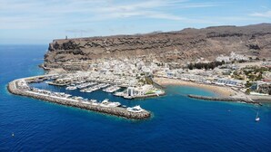 An aerial view of a coastal town with a marina, buildings, and a mountainous backdrop. - Casa Salome by El Sirocco (Lomo Quiebre)