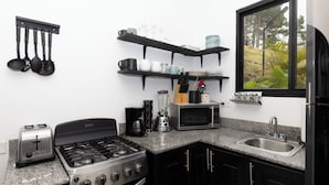 A kitchen with a gas stove, toaster, microwave, and a sink. - Cozy Hideaway in the Mountains of Altos de María (Sorá)