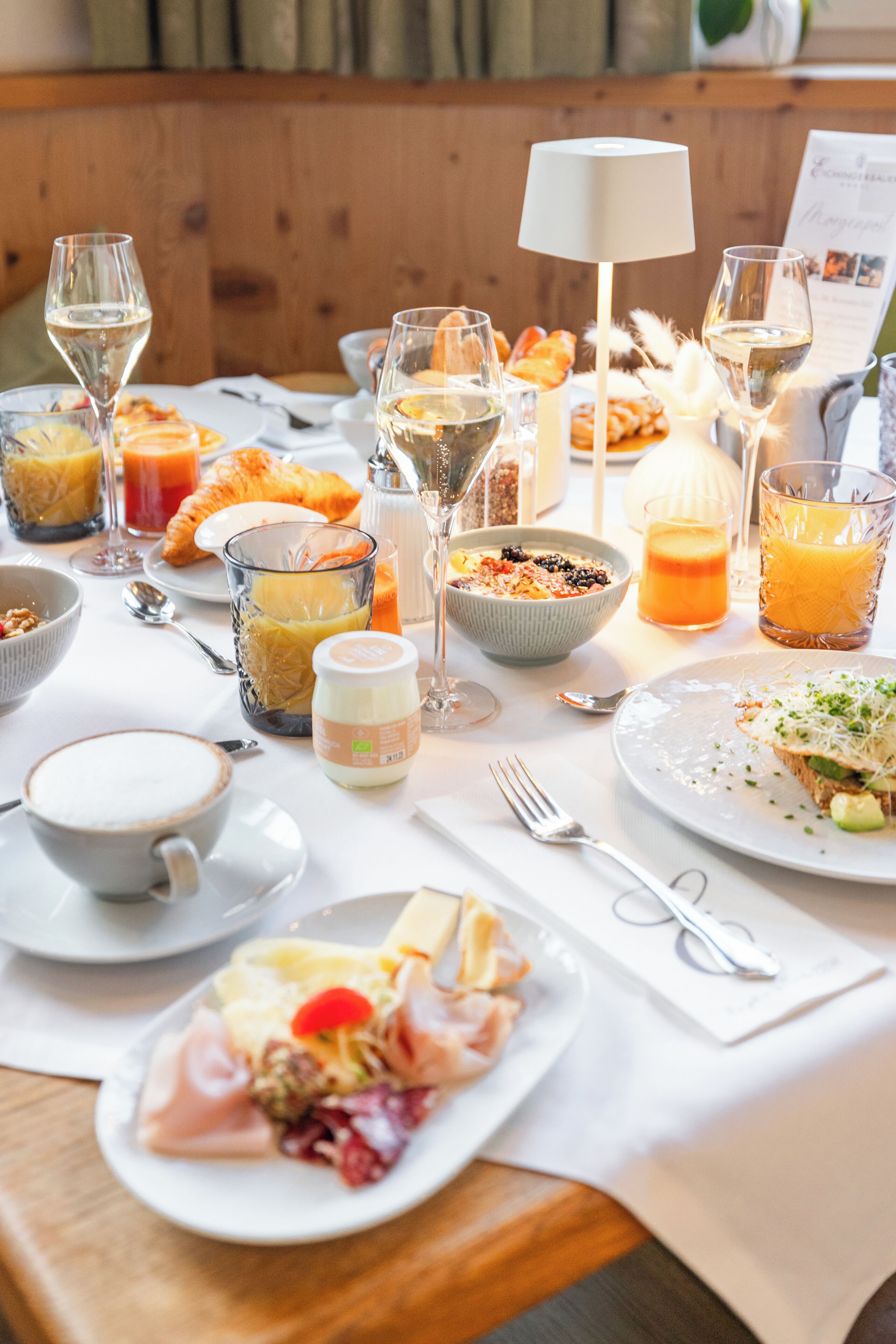 A breakfast setting with various dishes, drinks, and utensils on a table.