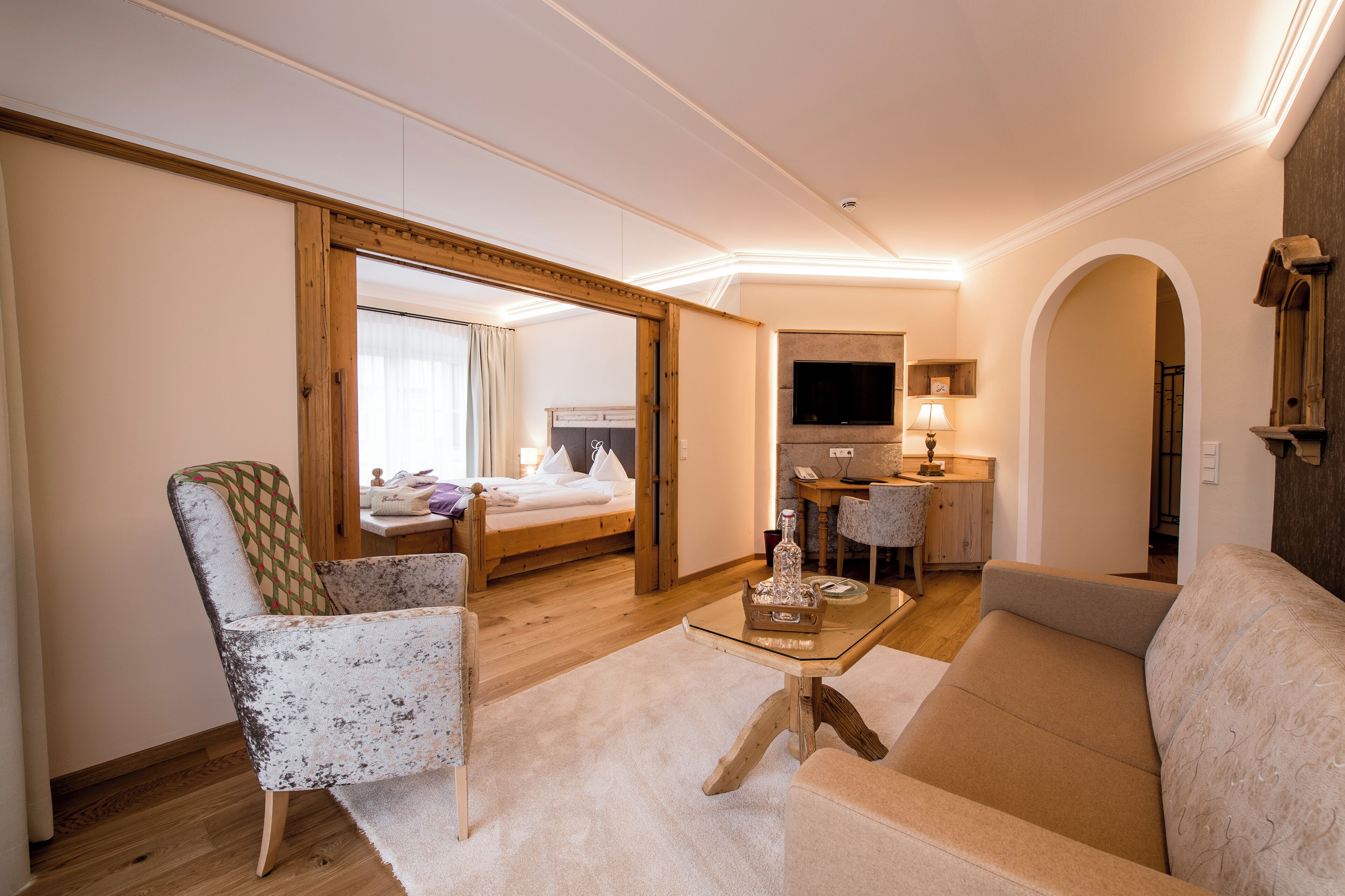 Une chambre d’hôtel comprenant un lit, un canapé, une chaise, une télévision, un bureau et un miroir.