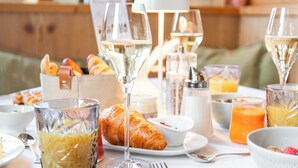 Een ontbijttafel met croissants, fruit en drankjes.