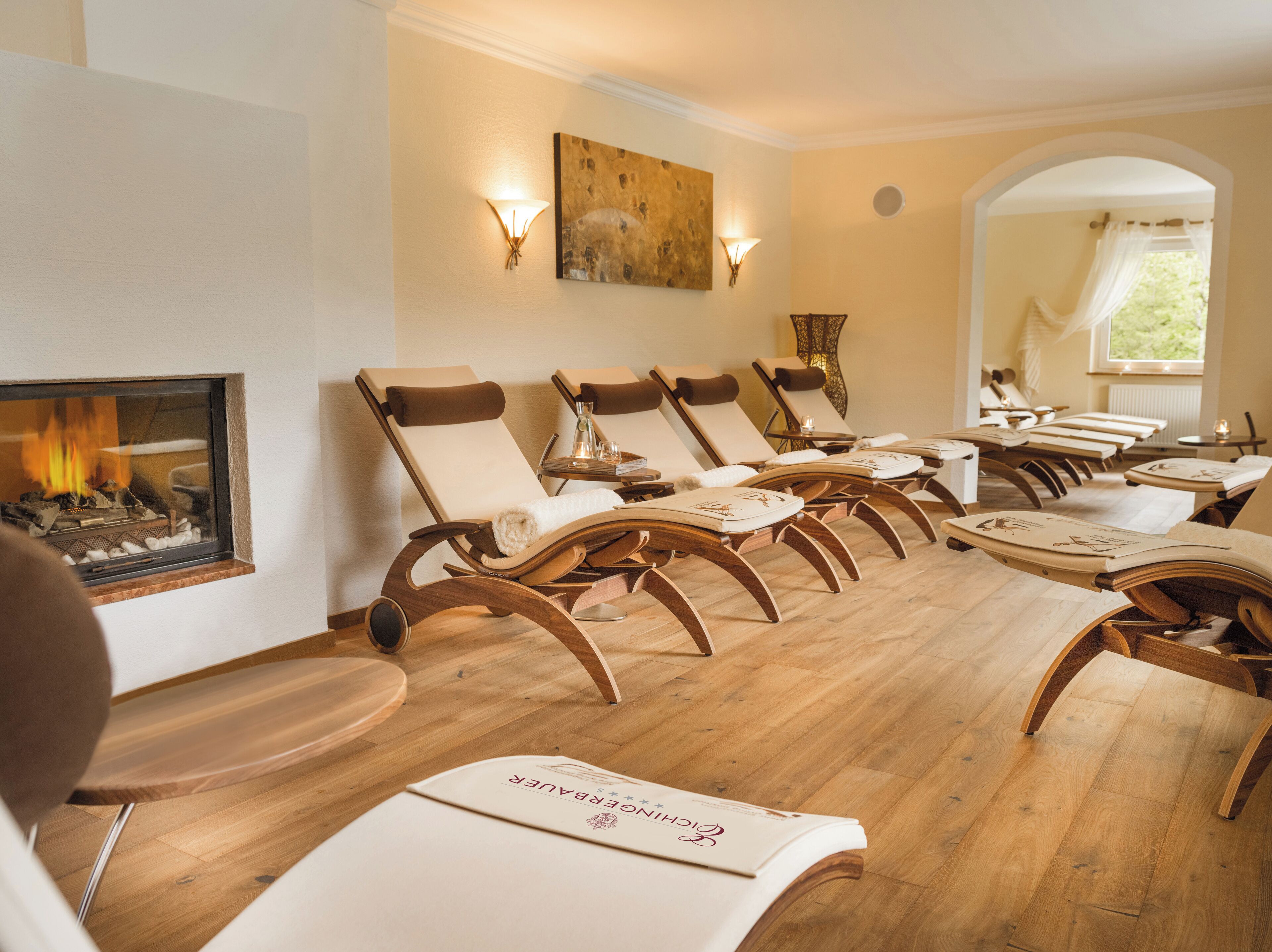 Una habitación con piso de madera, paredes color beige y una chimenea. Hay varios sillones dispuestos en fila.