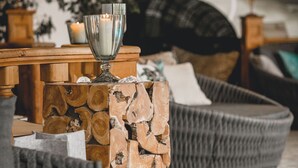 Een gezellige zithoek met een houten tafel, een glazen kandelaar en een stenen muur.
