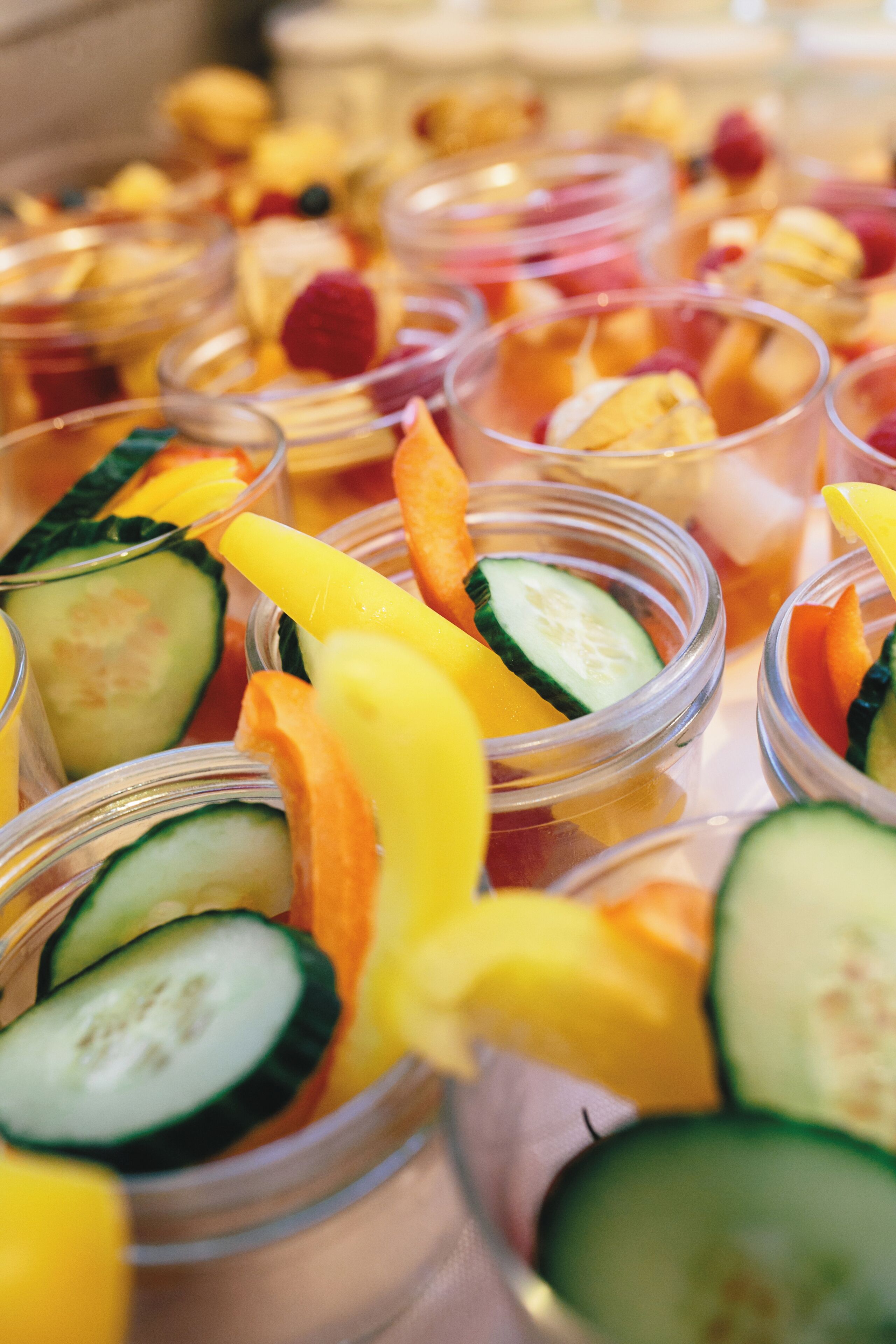 Multiple clear glass containers filled with sliced fruits and vegetables.