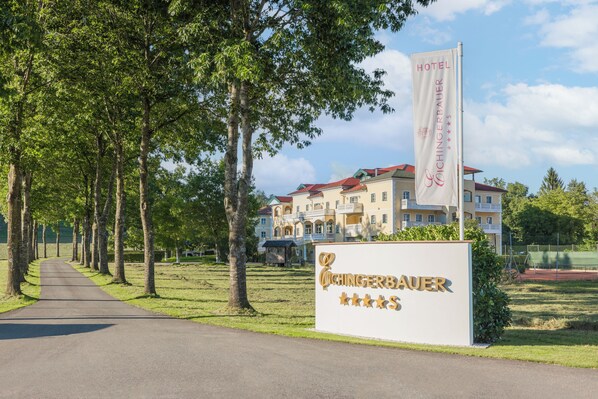 A hotel sign with a five-star rating and a building with multiple balconies in the background. - Hotel Eichingerbauer (Sankt Lorenz)