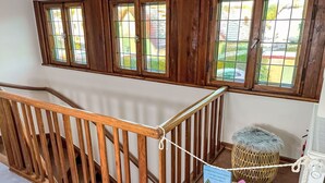 Un escalier en bois avec une rampe, un panier en osier contenant divers objets et un panneau avec du texte en allemand.