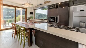 A modern kitchen with a central island, stainless steel appliances, and a large window overlooking a balcony. - Stunning private villa for 7 people with WIFI, private pool, patio, pets allowed and panoramic v... (Scarlino)
