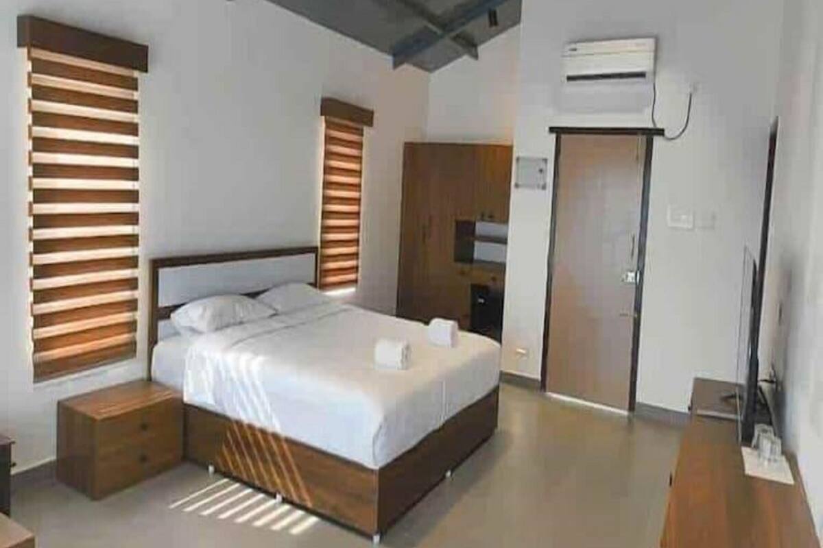 Une chambre moderne avec un grand lit, une tête de lit en bois et des rangements intégrés.