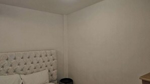 A bedroom with a tufted headboard, a small bedside table, and a nightstand.