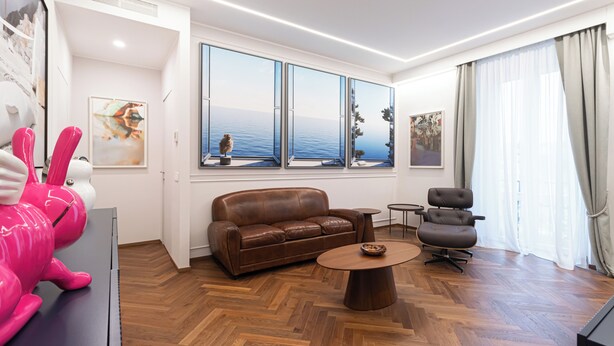 A modern living room with a leather sofa, a round coffee table, and a view of the sea through large windows. -  Italianway - XXV Aprile 7 B - Smeraldo (Milan)