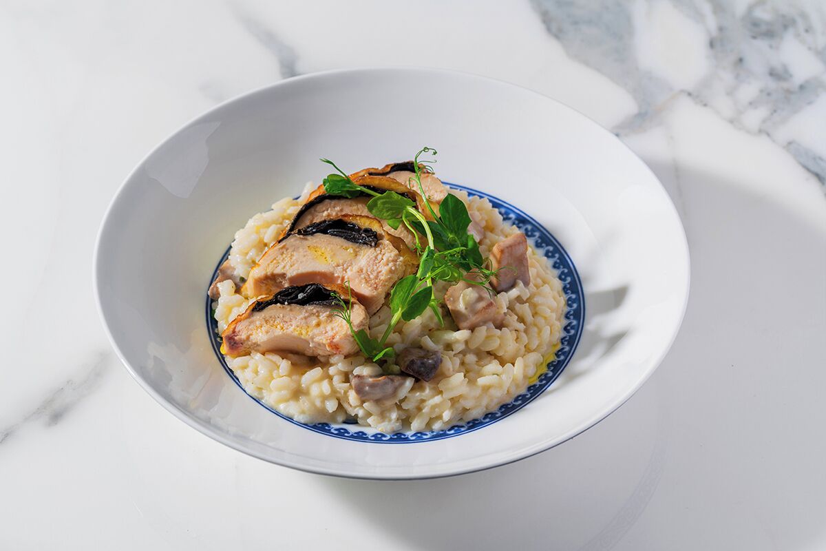 A bowl of chicken and rice with mushrooms and herbs.