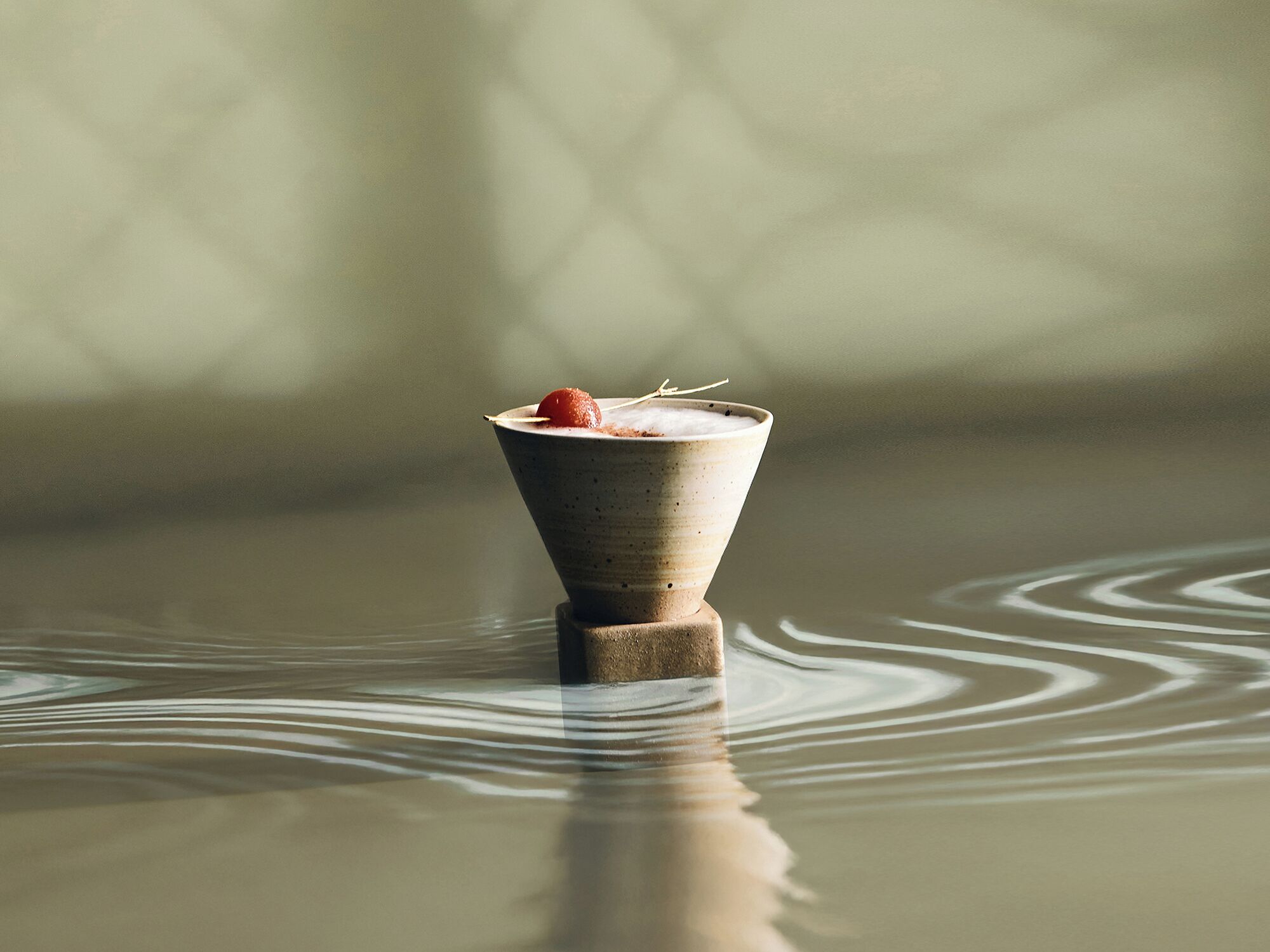 A ceramic cup with a dessert on a reflective surface.