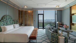 Ein Hotelzimmer mit einem großen Bett, einer Couch, einem kleinen Tisch und Blick auf die Stadt.