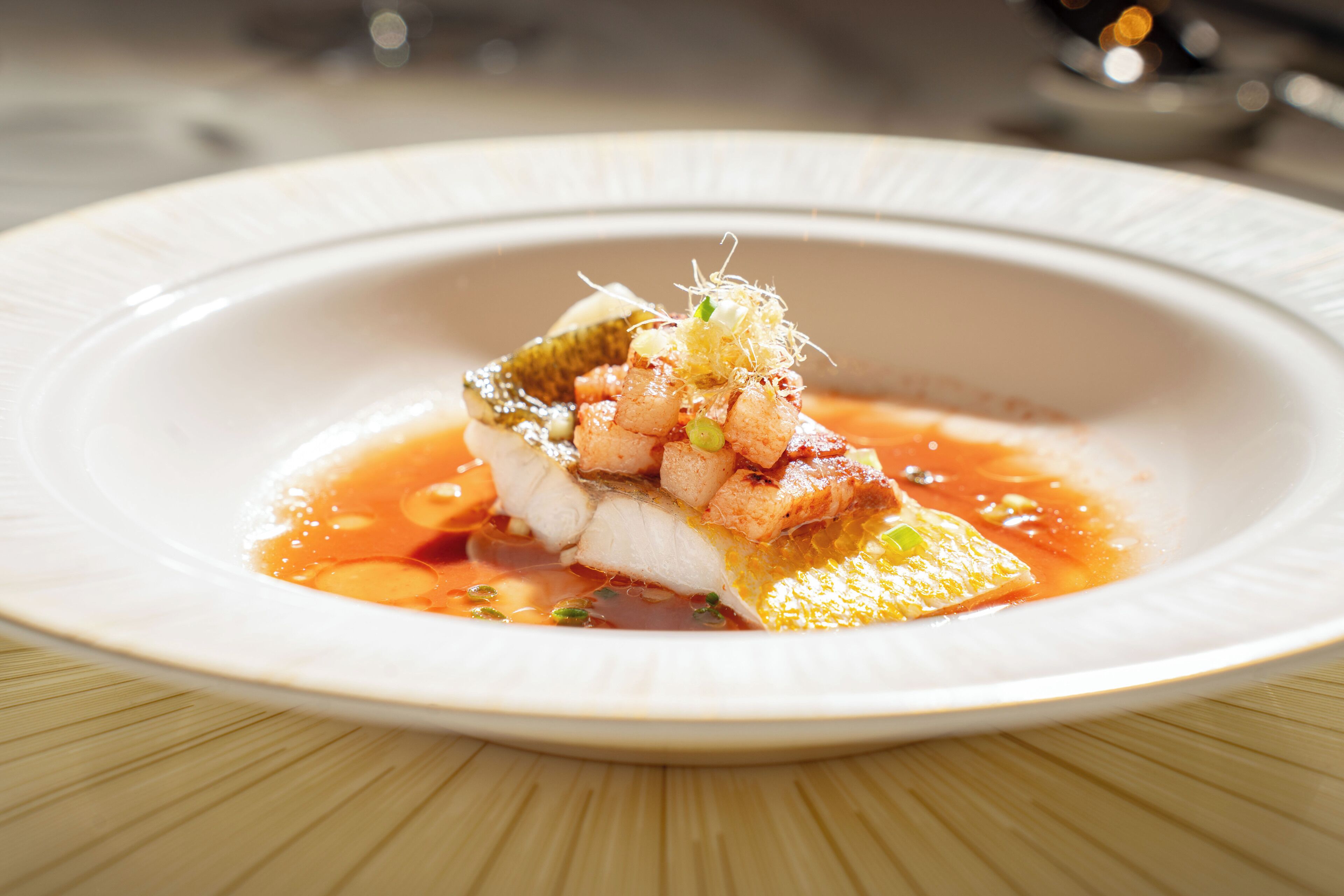 A white plate with a seafood dish, garnished with green onions and a sauce.