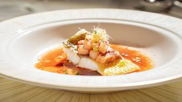 Une assiette blanche contenant un plat de fruits de mer, garni d’oignons verts et d’une sauce.