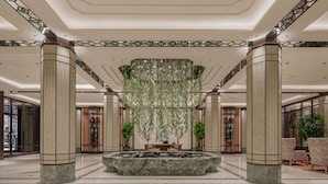 Eine großzügige Lobby mit einer zentralen Marmorfountain, hohen Decken und stattlichen Säulen.