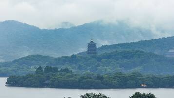Um pagode numa colina com vista para um lago, rodeado por uma floresta densa.
