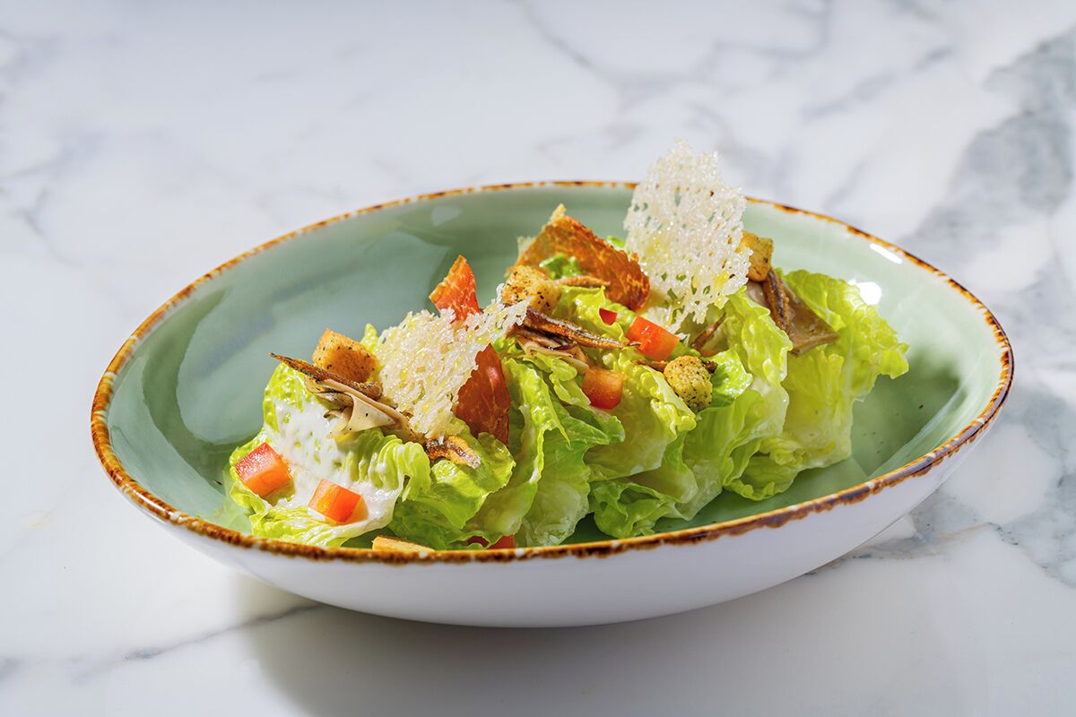 A bowl of salad with lettuce, tomatoes, and croutons on a ceramic plate.