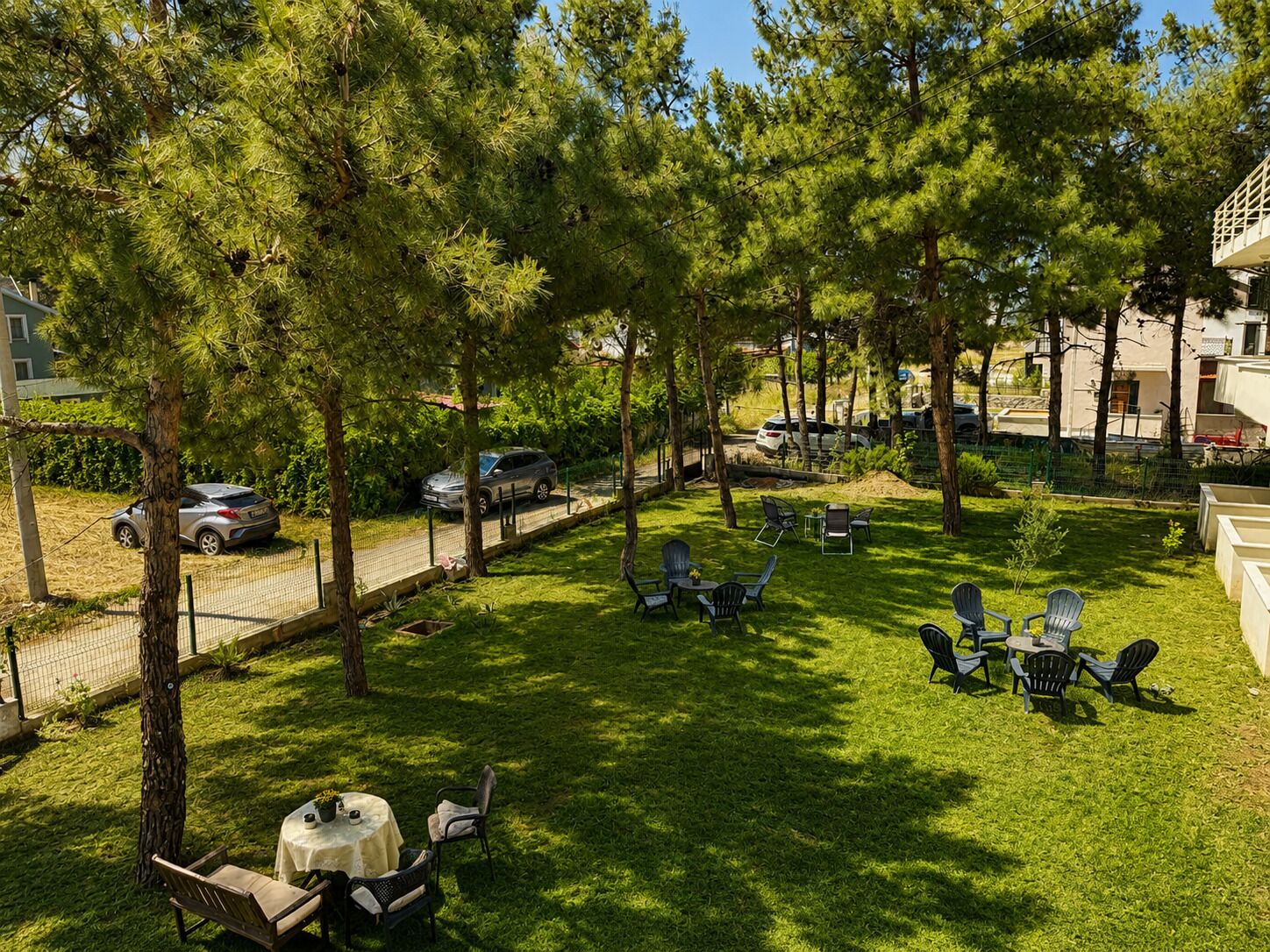 Zona exterior amb gespa, arbres, una tanca i mobiliari exterior.