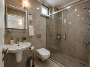 A modern bathroom with a glass shower enclosure, a sink, a toilet, and a mirror.