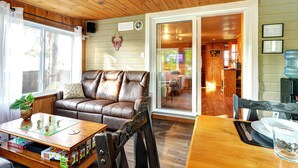 A cozy living room with a leather sofa, wooden coffee table, and a dining area with a wooden table and chairs.
