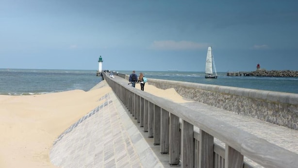 A coastal walkway with a lighthouse and a sailboat in the distance. - Domitys Le fil de soie  (Calais)