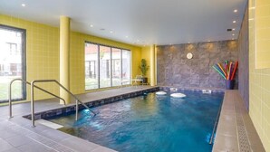 A swimming pool with a tiled deck, a metal ladder, and a stone wall. - Domitys Le fil de soie  (Calais)