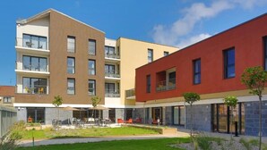 A modern apartment complex with multiple balconies, outdoor seating areas, and a well-maintained courtyard. - Domitys Le fil de soie  (Calais)
