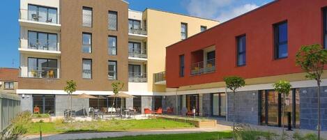 A modern apartment complex with multiple balconies, outdoor seating areas, and a well-maintained courtyard.