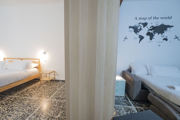 Une chambre avec deux lits, une tête de lit en bois, une petite table de chevet et une carte du monde accrochée au mur.
