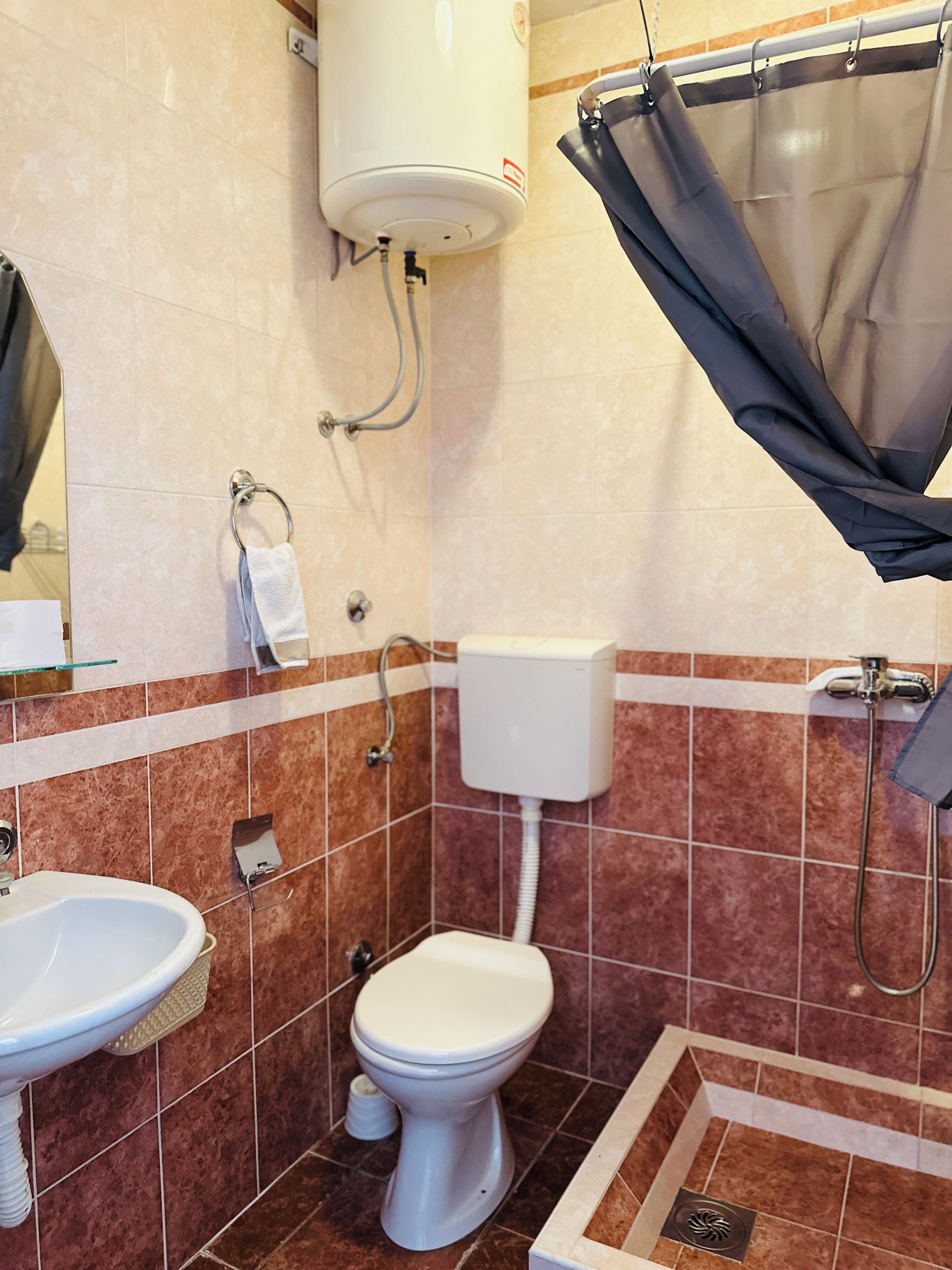 A bathroom with a toilet, sink, shower, and a towel rack.