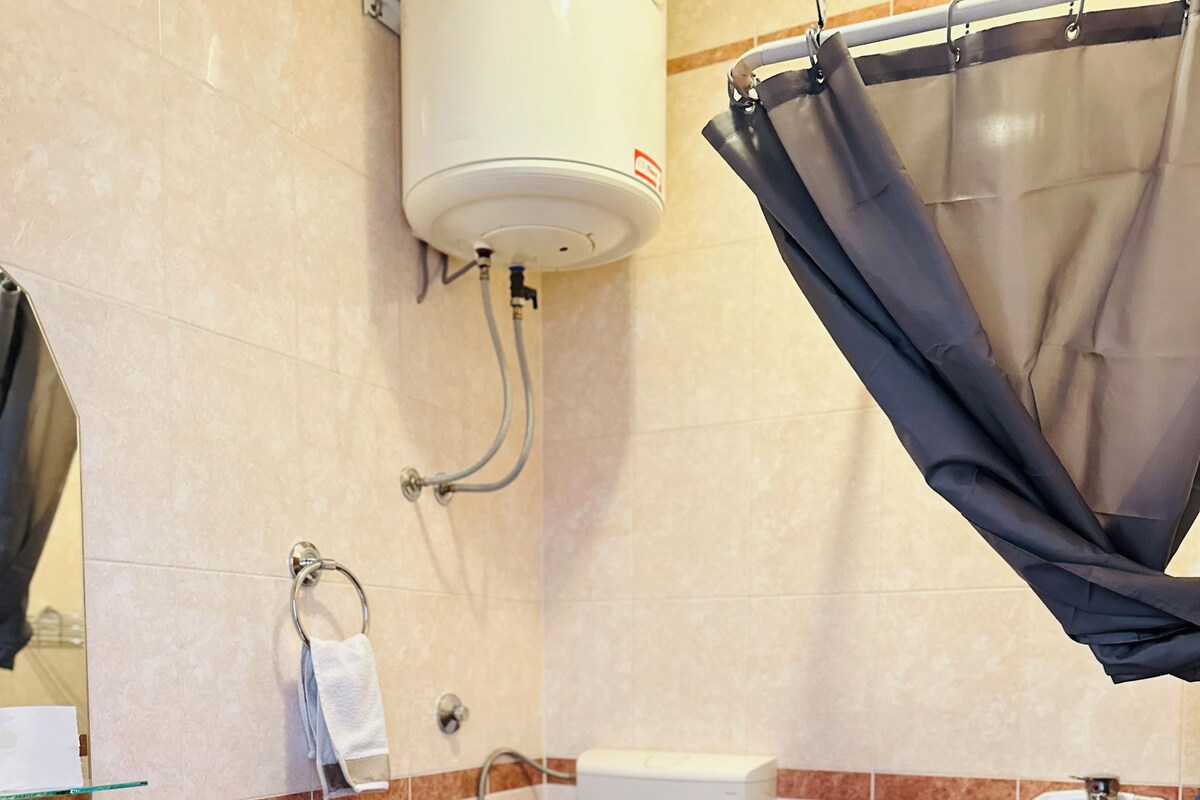 A bathroom with a toilet, sink, shower, and a towel rack.