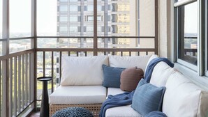 A balcony with a sofa, ottomans, and a small table. - Downtown Hidden Gem w/ Balcony & Free Parking (Atlanta)