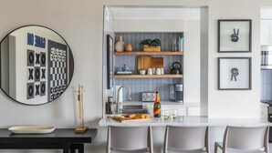 A modern kitchen with a central island, bar stools, a round mirror, and framed artwork on the walls. - Downtown Hidden Gem w/ Balcony & Free Parking (Atlanta)