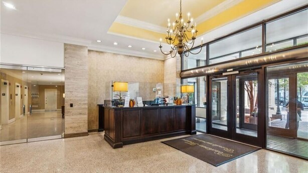 A hotel lobby with a reception desk, a chandelier, and a glass door entrance. - Downtown Hidden Gem w/ Balcony & Free Parking (Atlanta)