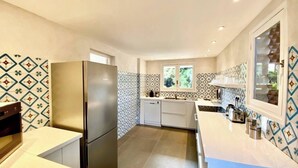 Una cocina moderna con refrigerador de acero inoxidable, encimeras blancas y azulejos decorativos en la pared.