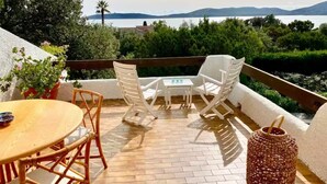 Una terraza con una mesa y sillas, una silla de mimbre, una mesa de mimbre y una lámpara de mimbre.