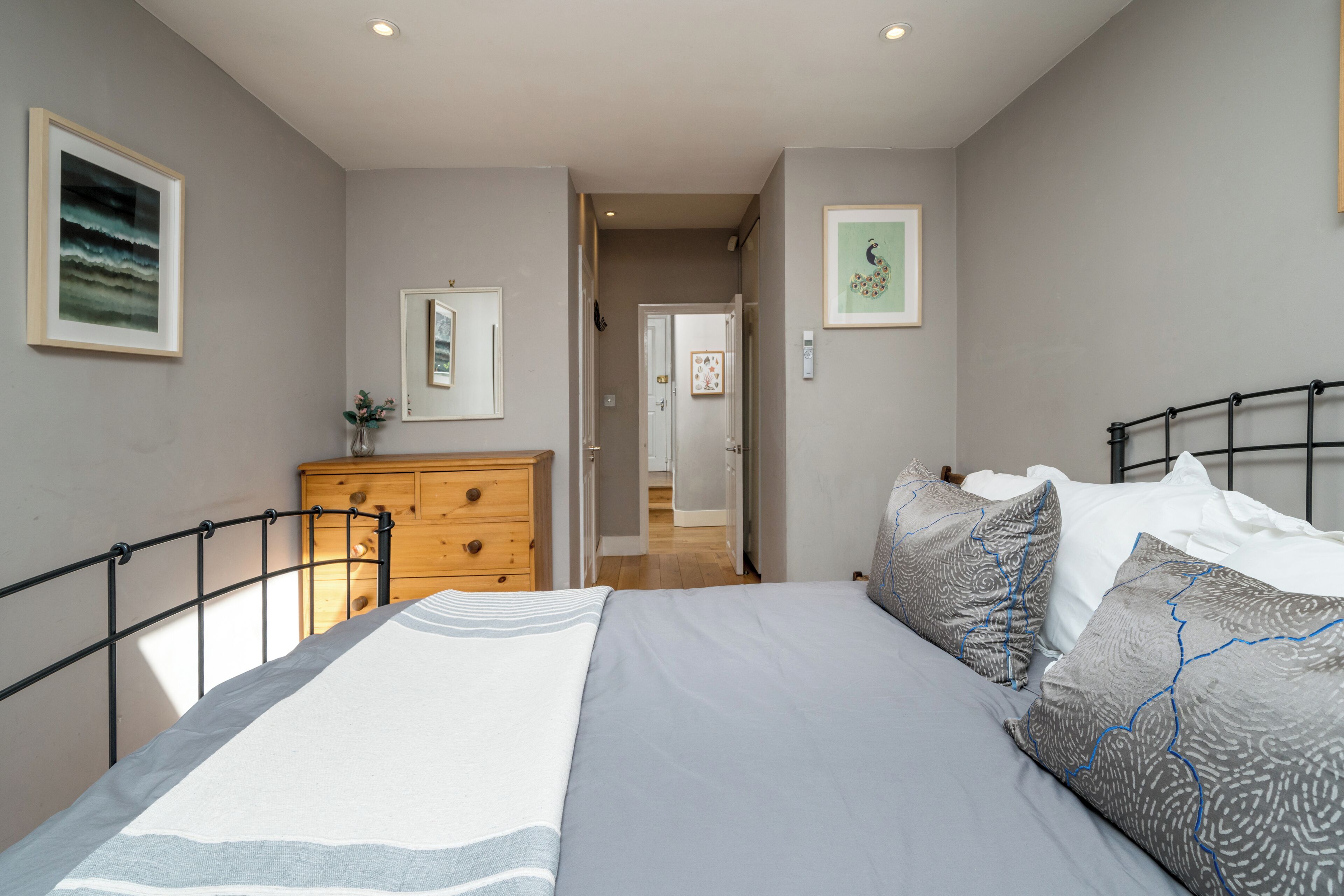 A bedroom with a bed, dresser, and framed pictures on the walls.