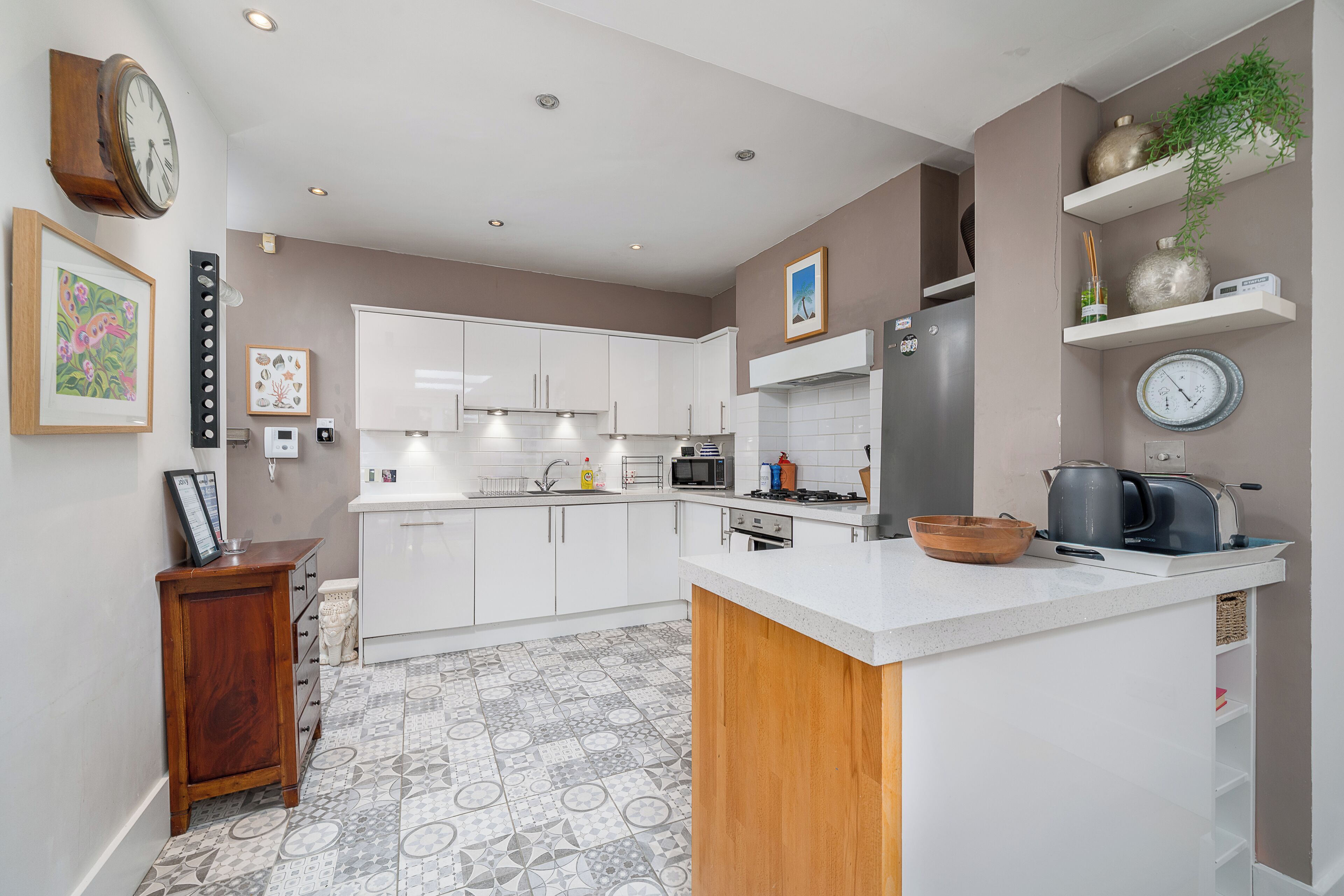 A modern kitchen with white cabinets, a central island, and a microwave.