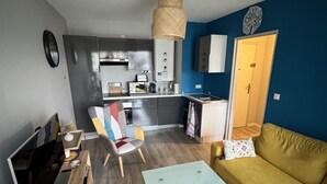 Un espacio habitable compacto con kitchenette, un sofá, una mesa de comedor y un televisor.