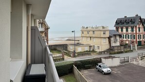 Un balcón con vista a una playa y edificios al fondo.