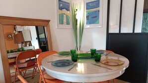Un comedor con una mesa redonda, sillas naranjas y copas de vidrio verde.