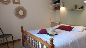 Un dormitorio ordenado con una cama de madera, una silla y decoraciones en la pared, incluyendo un espejo y obras de arte.