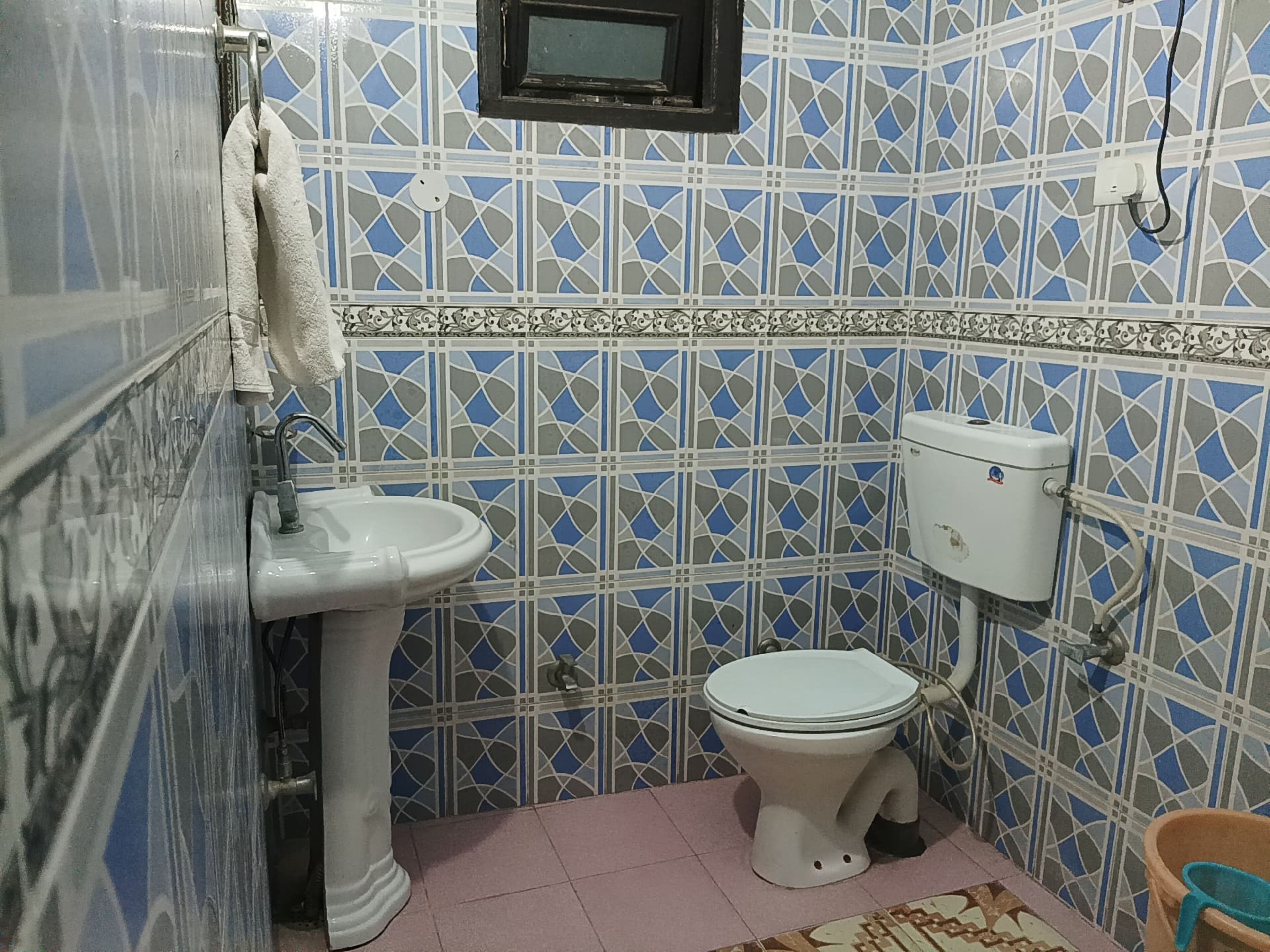 A bathroom with a white sink, toilet, and a small window above the toilet.