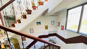 A multi-level interior with a staircase, potted plants, and framed pictures on the walls. - Hotel D Pal (Kandaghat)