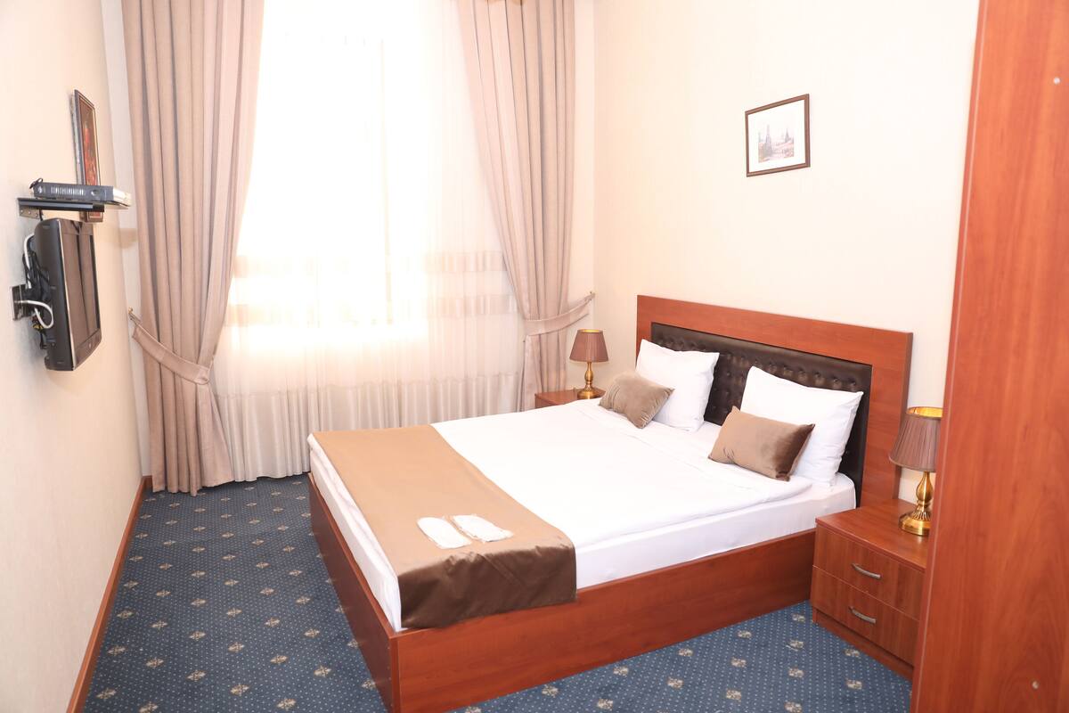 A hotel room with a large bed, a bedside table, a lamp, and a picture on the wall.