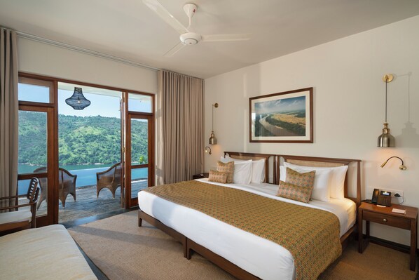 Habitación de hotel con una cama grande, un escritorio y vistas a un paisaje pintoresco por las ventanas.