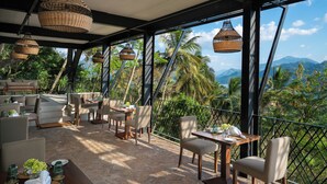 Una terraza con lámparas colgantes de mimbre, mobiliario exterior y vistas a palmeras y montañas.